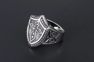 Close-up of retro titanium steel ring with embossed cross shield design and floral texture