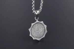Détail macro du pendentif soleil en acier titane argenté avec texture martelée et chaîne