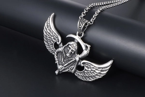 Macro shot of gothic grim reaper pendant with detailed wings and scythe in silver steel