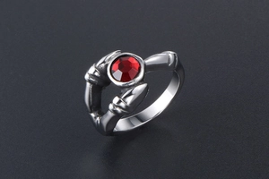 Detail of gothic stainless steel ring featuring three claws holding a round red gemstone
