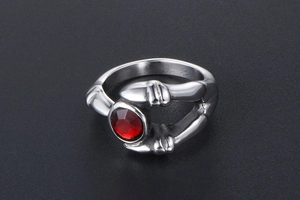 Gothic silver beast claw ring with a deep red round gemstone in a macro detail view