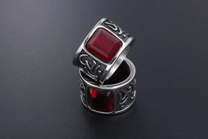 Macro view of wide titanium steel ring with a large red stone and tribal carvings
