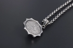 Gros plan détaillé du pendentif en acier titane argenté avec bords dentelés et zircon bleu