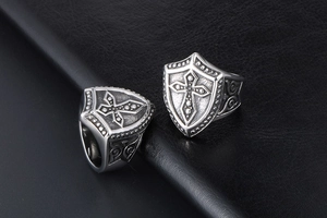 Detail of vintage titanium steel signet ring featuring a cross shield and scrollwork