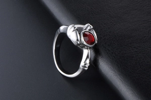 Detailed close-up of Gothic silver ring with a red oval gemstone on black leather