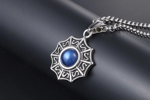 Détail macro du pendentif engrenage en acier avec pierre œil de chat bleue et chaîne