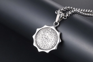 Détail macro du pendentif en acier titane avec disque texturé et chaîne à maillons