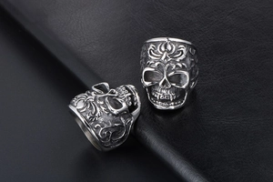 Macro shot of vintage punk skull rings with intricate vine patterns on black leather