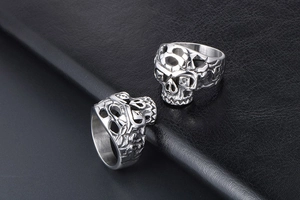 Detailed close-up of two silver skull rings in punk style with intricate hollow engraving