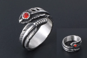 Detail of vintage feather ring in stainless steel with a red gemstone on dark background