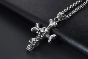 Close-up of gothic double skull cross pendant on a thick chain with black leather background