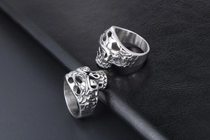 Detailed view of silver skull punk ring with intricate hollow engraving on leather base