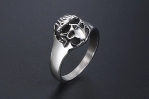 Gros plan sur une bague tête de mort argentée punk avec détails vintage noirs
