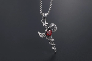 Macro shot of gothic angel sword pendant with red heart zircon and snake detail