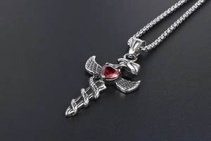 Macro shot of silver gothic sword cross pendant with red heart stone and snake detail