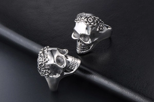 Close-up of vintage skull and flower engravings on silver polished titanium steel men's rings