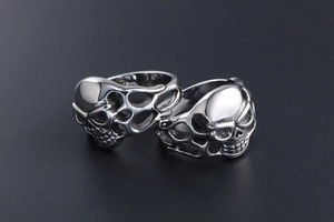 Gothic skull rings with hollow mesh band in silver steel on a matte black surface