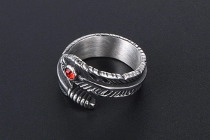 Macro detail of gothic feather ring in titanium steel with a vibrant red crystal stone