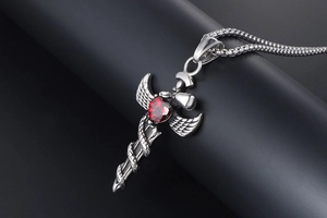 Detail of gothic sword pendant featuring a red heart stone and intricate snake texture