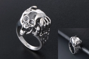 Detailed view of silver skull ring with punk skeleton hand grip in vintage stainless steel