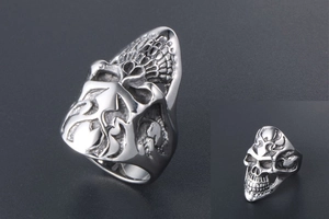 Detailed close-up of a silver gothic skull ring with side floral relief and steel texture