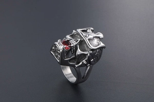 Macro shot of gothic skull ring with red gemstone and intricate silver engravings