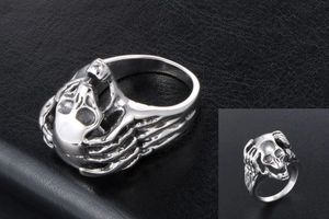 Macro shot of silver skull ring with gothic wing details on black leather background