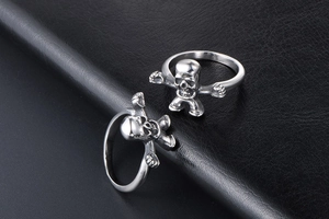 Detailed view of silver skull rings featuring unique skeleton figures on black leather