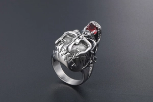 Detail of gothic silver ring featuring a red faceted gemstone and 3D skull crown carving