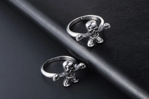 Macro detail of silver skull figurine rings on a black leather background