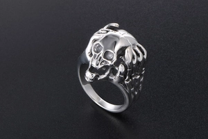 Detailed view of punk skull ring with skeletal hands in retro silver stainless steel