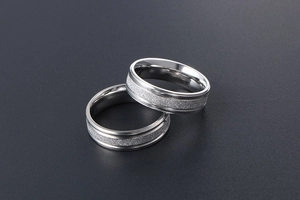 Detail of silver couple rings showing brushed finish and polished edges in macro view