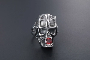 Macro shot of retro silver skull ring with crown and sparkling red zircon inlay