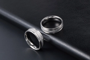 Macro shot of matte and polished stainless steel couple rings on black leather texture