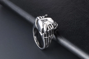 Macro detail of silver skull ring with bone hand carvings and vintage polished finish