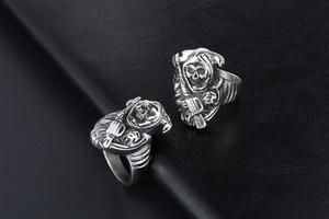 Detailed view of punk gothic grim reaper rings with scythe on black leather background