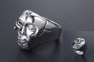 Détail macro d'une bague gothique en acier avec visage sculpté et motif de crâne