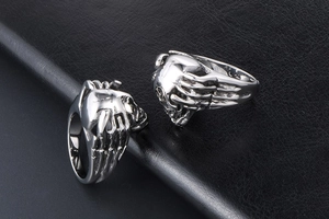 Detailed view of two silver skull hand rings with gothic relief on black leather