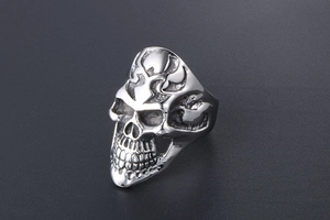 Detailed close-up of a punk skull ring in silver stainless steel with gothic flame carvings