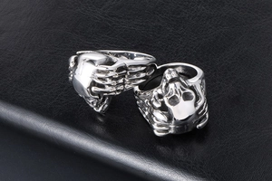 Detail of vintage punk skull and skeletal hand rings in silver-tone stainless steel