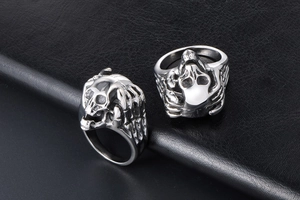 Detailed view of silver stainless steel skull and bone hand rings on black leather