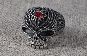 Macro side view of gothic skull ring in antique silver finish with a red gemstone eye