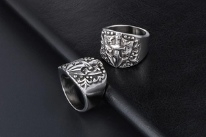 Detailed close-up of gothic stainless steel cross and sword rings on black leather