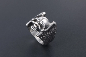 Detailed view of silver skull ring with angel wings and vintage steel finish texture