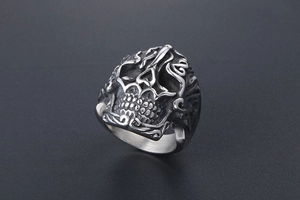 Detail of vintage skull ring featuring embossed cloud patterns and oxidized steel finish