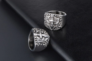Close-up of gothic stainless steel rings featuring embossed crosses and crest designs