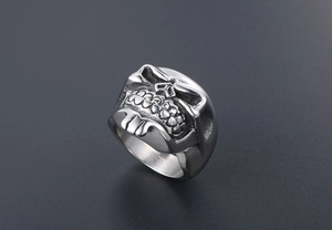 Macro detail of men's punk skull ring showing intricate facial carving and steel texture