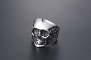 Détail macro d'une bague tête de mort gothique avec des gravures d'ailes en acier poli
