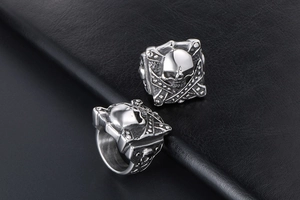 Detailed close-up of polished silver skull rings on a premium black leather texture
