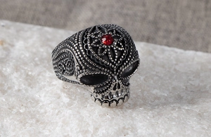 Macro view of punk skull ring in silver steel with red gemstone and beaded detail